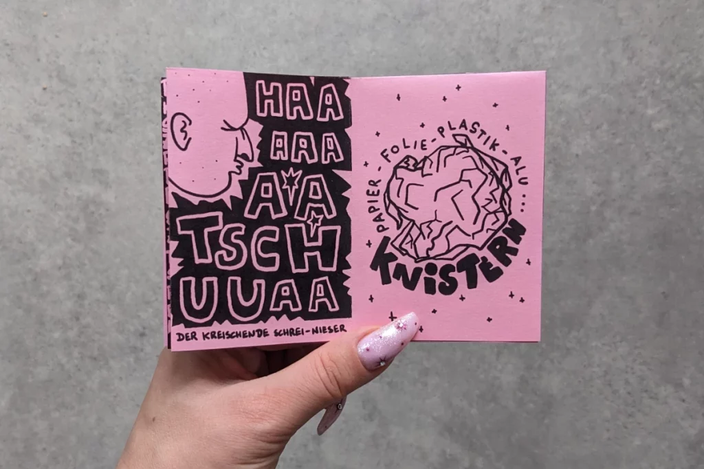 Geöffnete Doppelseite: Zeichnung niesendes Gesicht. Sehr große gemalte Buchstaben "HATSCHUA". Zeichnung geknüllte Papierkugel: Knistern.