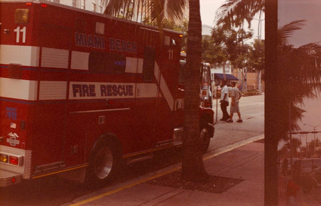 Roter „Miami Beach Fire Rescue“-Wagen parkt an einer von Palmen gesäumten Straße.