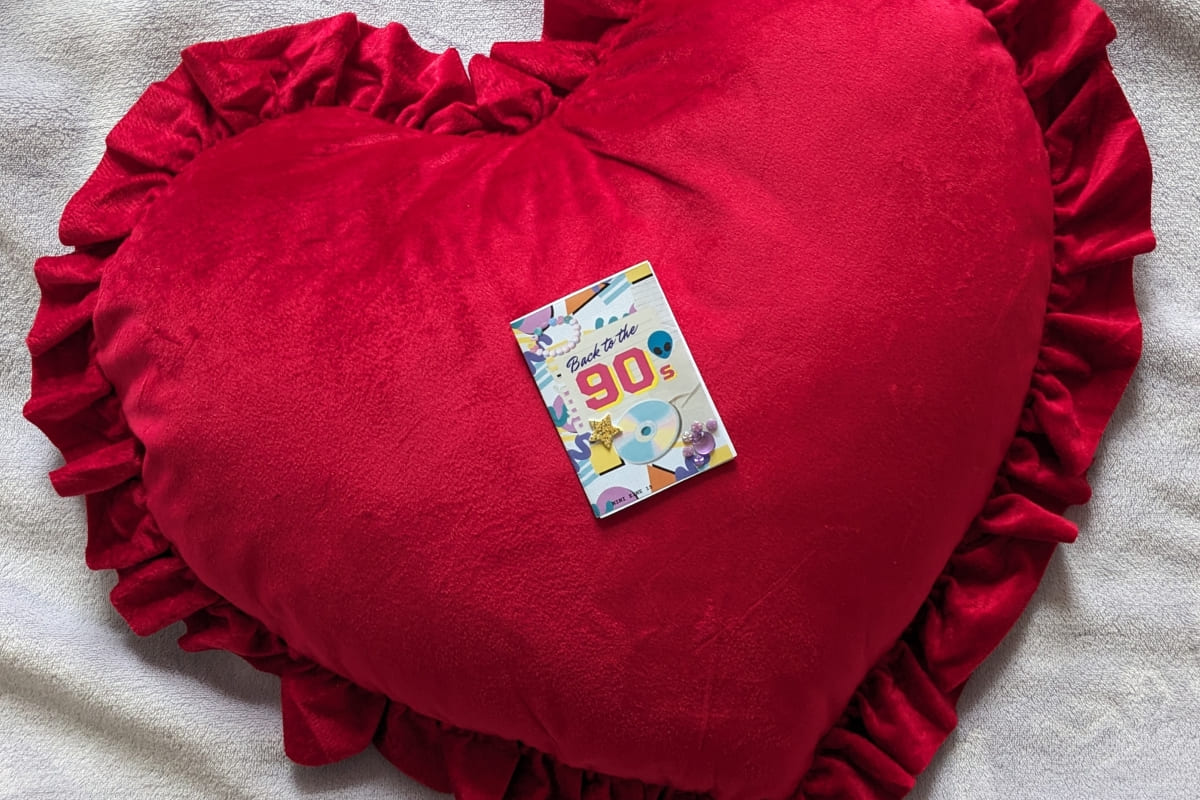 Buntes Mini Zine liegt auf einem großen roten Plüschherz
