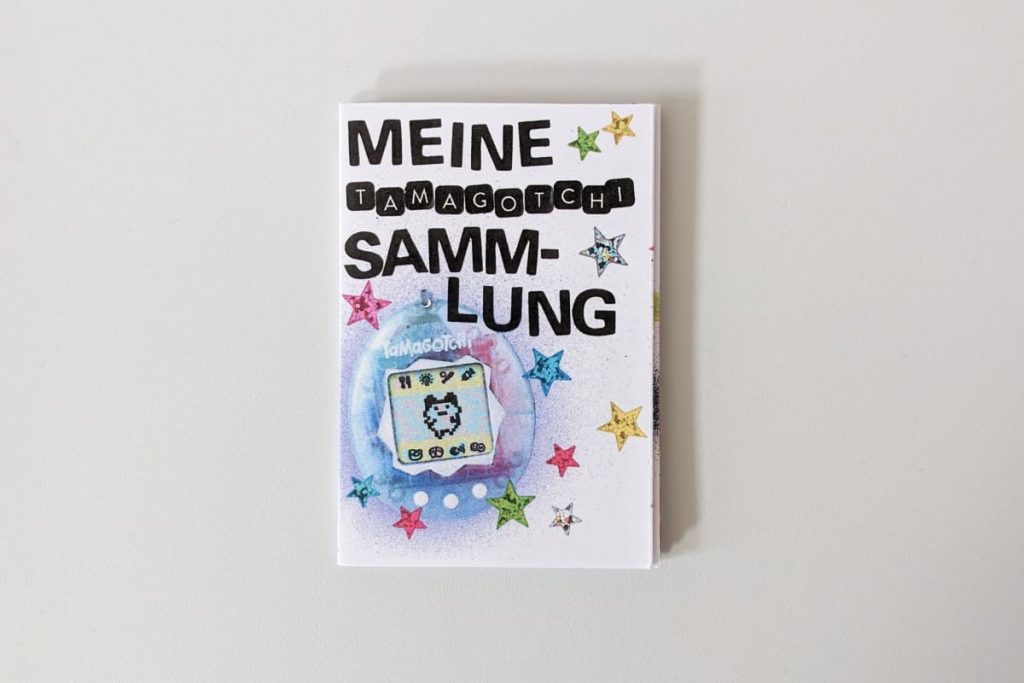 Zine-Cover „MEINE TAMAGOTCHI SAMMLUNG“ mit einem blauen Tamagotchi und bunten Sternen.
