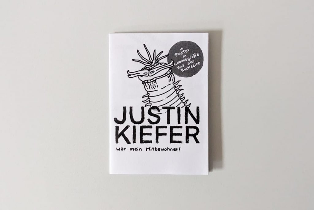 Cover eines schwarz-weißen Zines mit der Aufschrift „JUSTIN KIEFER war mein Mitbewohner!“ und der Zeichnung einer Kreatur.