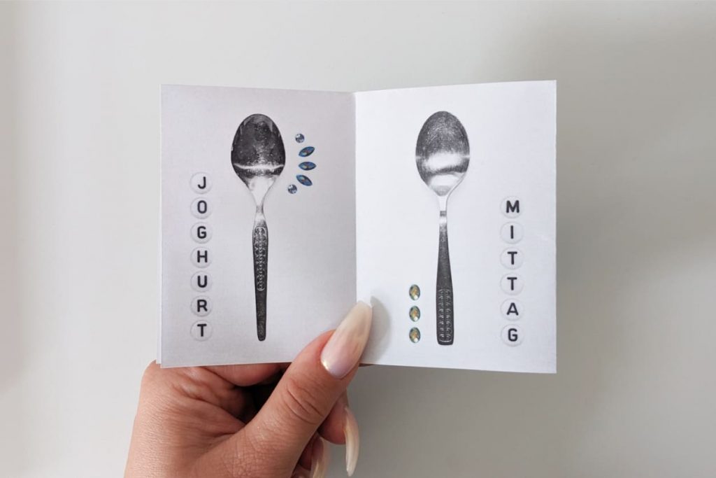 Offenes Zine: Links ein Esslöffel mit breitem tropfenförmigem Löffelblatt (JOGHURT). Rechts ein Esslöffel mit gleichmäßig ovalem Löffelblatt (MITTAG). Beide mit reliefartig strukturiertem DDR-Retro-Griff.
